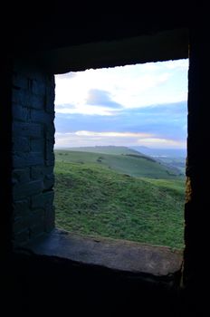 Looking out through an opening onto lush rolling countryside.