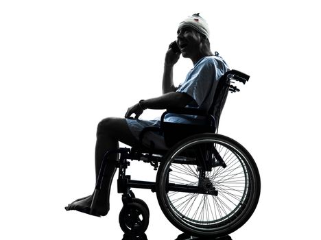 one injured man on the telephone surprised in wheelchair in silhouette studio on white background