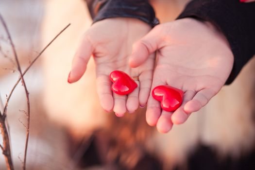 Woman's and men's hands holding pair of hearts as a symbol of love