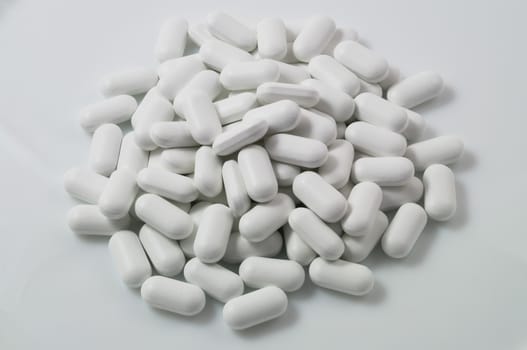 White pills scattered on a white background.