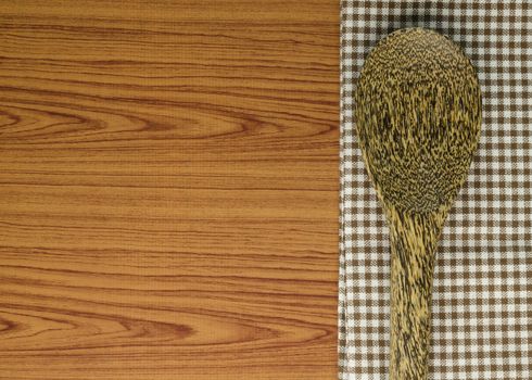 brown kitchen towel with spoon on wood background