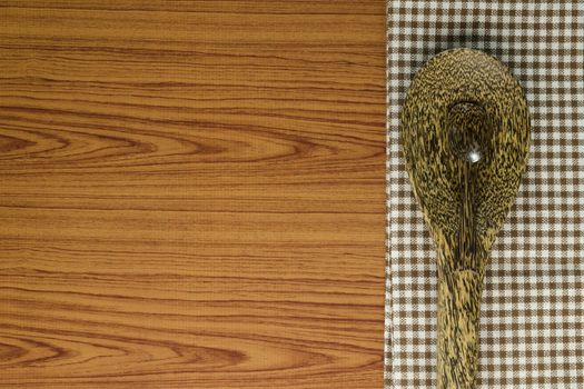 brown kitchen towel with spoon on wood background