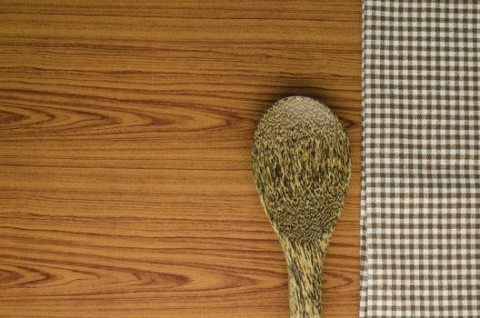 brown kitchen towel with spoon on wood background