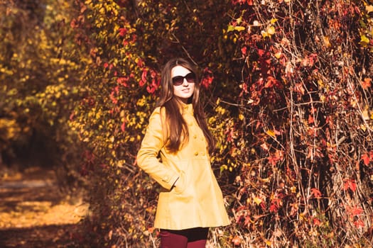 Woman is walking in autumnal park in glasses