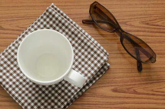 empty coffee cup on brown kitchen towel and wood table