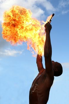 Circus fire-eater blowing a large flame from his mouth