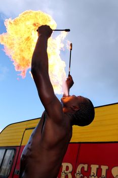 Circus fire-eater blowing a large flame from his mouth