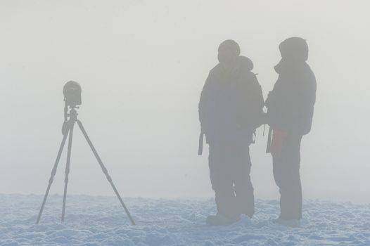 Silhouette of photographers with tripod  in the fog. 