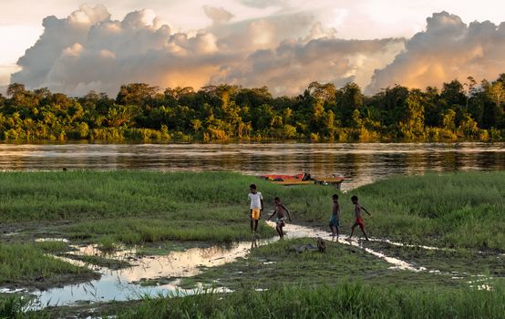  NEW GUINEA, INDONESIA - JUNY 26: Unknown children play on the river bank, near the village. Decline, end of day. June 26, 2012 in  Village, New Guinea, Indonesia 