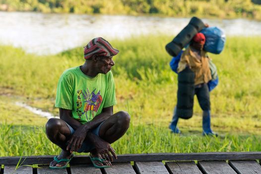  NEW GUINEA, INDONESIA - JUNE 26: The local Papuan man  observes as the porter transfers baggage. On June 26, 2012 in  Unknown Village, New Guinea, Indonesia 