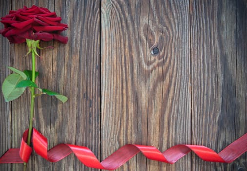 Red rose border with decorative ribbon over old wood 