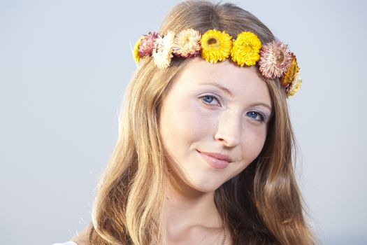 Beautiful young woman in a meadow wearing a crown of flowers