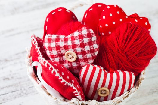 Valentine decorations: textile red hearts in white basket on the shabby table