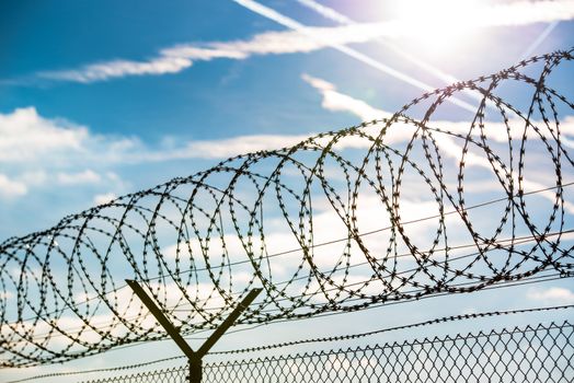 fence with barbed wire in front of great blue sky - concept for freedom, liberty or prison