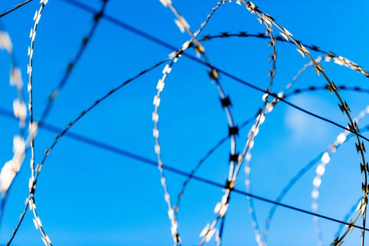 fence with barbed wire in front of great blue sky - concept for freedom, liberty or prison