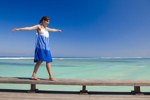 Beautiful woman walking with arms open on a beautiful tropical beach