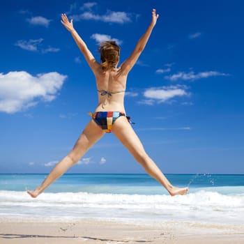 Beautiful and athletic young woman enjoying the summer, jumping in a tropical beach