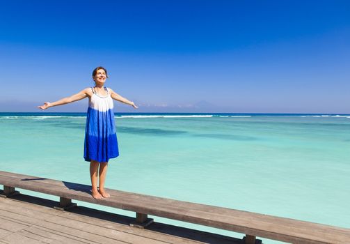 Beautiful woman walking with arms open on a beautiful tropical beach