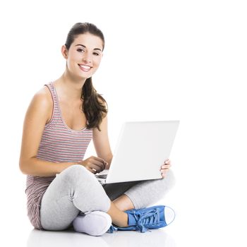 Beautiful student sitting in the floor with a laptop, isolated over a white background