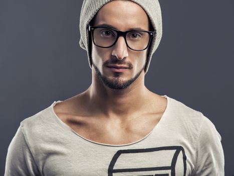 Casual portrait of a young man wearing a cap, over a blue background