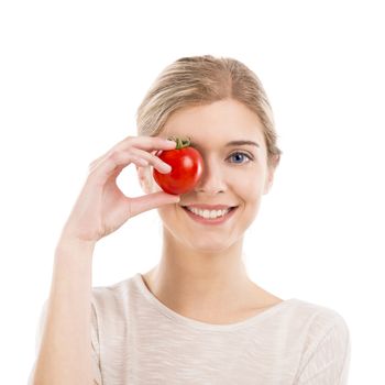 Beautiful girl smiling and holding a red tomato in front of the right eye, isolated over a white background