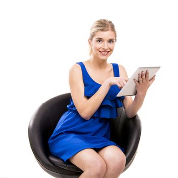 Beautiful woman sitting on a chair working with a tablet, isolated over white background