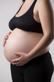 Pregnant woman showing her belly, over a gray background