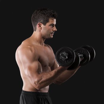 Portrait of a muscular man lifting weights against a dark background