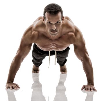 Muscle man dmaking push ups in studio, isolated over a white background