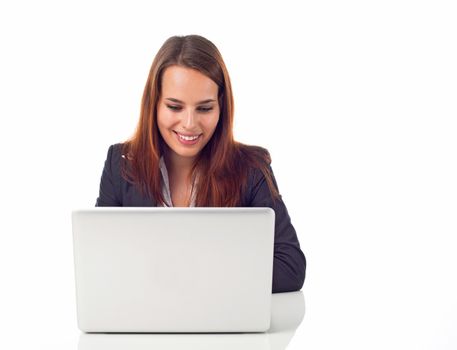 Young business woman working on her laptop and looking happy, isolated on white 