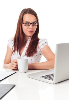 Beautiful young woman holding a cup of tea or coffee, in front a laptop, isolated on white 