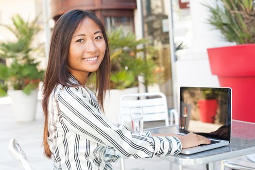 Happy asian woman working on her laptop, businesswoman or student