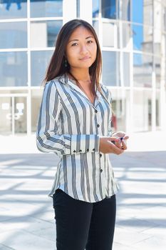 Portrait of a pretty asian businesswoman standing and holding a cell phone