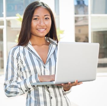 Portrait of an asian girl standing and using a laptop