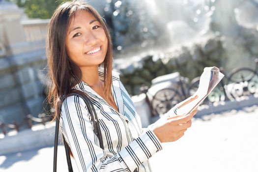 Asian tourist holding a city tour map and smiling