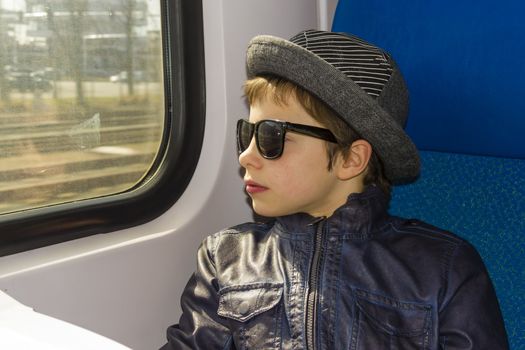 Handsome boy in sunglasses rides on a train