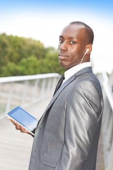 Portrait of a handsome businessman with hands-free headset and using electronic tablet