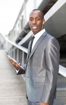 Portrait of a businessman with hands-free headset and using electronic tablet