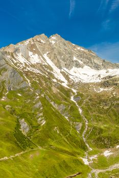 Mountain landscape with meadows and snow-capped summit