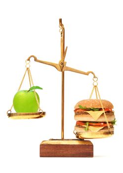 Unhealthy and healthy diet choices with burger outweighing an apple on weighing scales 
