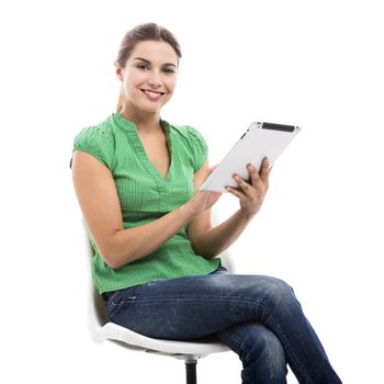 Beautiful female student sitting on a chair with a tablet, isolated over a white background