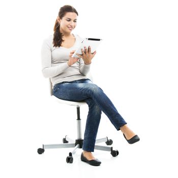 Beautiful female student sitting on a chair with a tablet, isolated over a white background