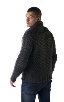 Attractive young man with wool sweater and jeans seen from the back, isolated on white background