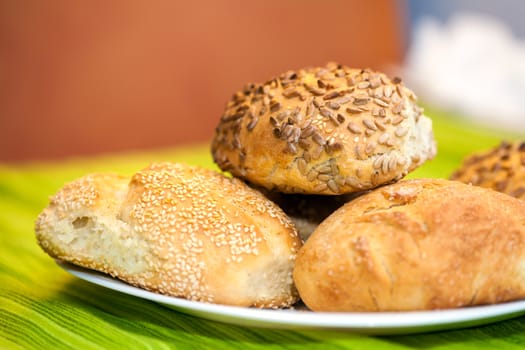 Fresh bread rolls with sunflower and sesame seeds on white plate table set