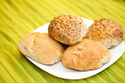 Fresh bread rolls with sunflower and sesame seeds on white plate table set