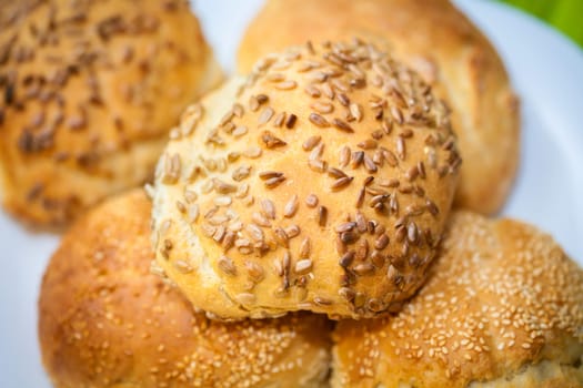 Fresh bread rolls with sunflower and sesame seeds on white plate table set