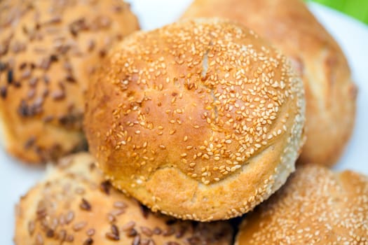 Fresh bread rolls with sunflower and sesame seeds on white plate table set