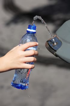 hand filling up water in a plastic bottle at a public spring fresh water fountain in paris