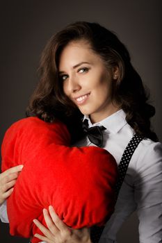 Beautiful girl holding a heart-shaped pillow in her arms.