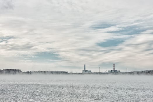 Nuclear power plant on the horizon line in winter and a nonfreezing technological reservoir